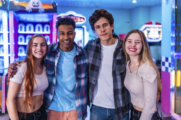 Four young multiethnic friends embrace, enjoying their weekend together at a vibrant bowling alley arcade