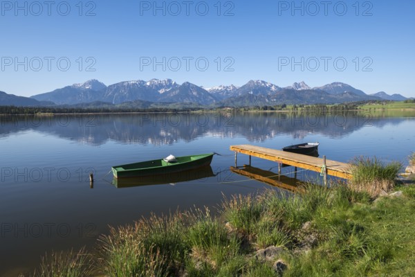 Jetty with green and black boats on a quiet lake in front of a mountain panorama, Hopfen am See, near Füssen, Ostallgäu district, Swabia, Bavaria, Germany, Europe
