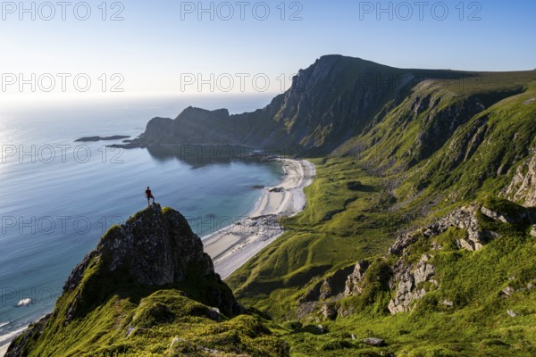 Climber on a rock, view of picturesque coastal landscape, steep coast with peak Måtind or Måtinden, Høyvika beach and sea, hike to the summit of Måtind, Andøya island, Vesterålen, Nordland, Norway, Europe