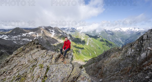 Mountaineer sitting on a rock, on a steep rocky ridge, on the summit of the Lasörling, view of the mountain panorama of the Venediger Group, Lasörling Group, Hohe Tauern National Park, East Tyrol, Tyrol, Austria, Europe