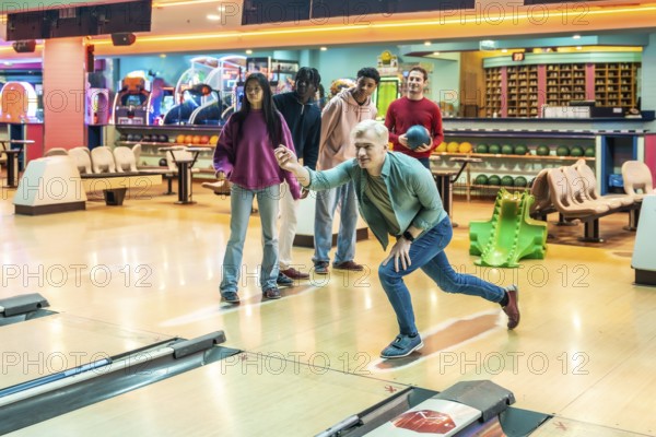 Diverse group of young adults having fun bowling together, enjoying a weekend leisure activity