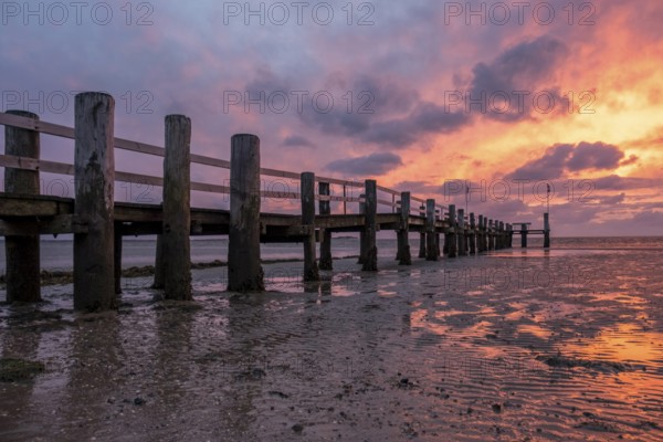 A jetty on the beach at sunset, the sky is coloured orange and purple, the water reflects the coloured sky, Utersum, Föhr, Nordfriesland, Schleswig-Holstein, Germany, Europe