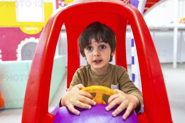 Preschooler having fun driving an imaginary car in kindergarten, engaging in playful learning and development