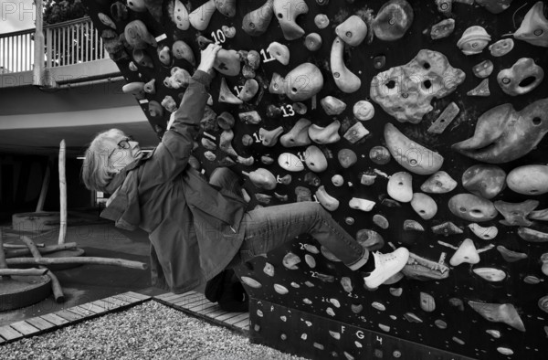 Elderly woman, 65 years old, climbing on climbing wall, urban, concrete, black and white, Stuttgart, Baden-Württemberg, Germany, Europe