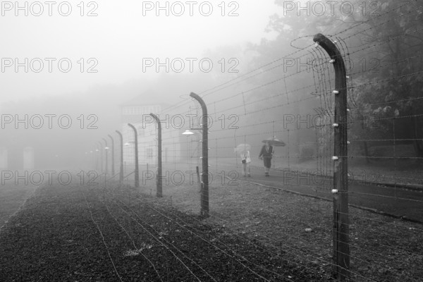 Reconstructed camp fence with people in the fog at beech forest concentration camp, now a concentration camp memorial, Weimar, Thuringia, Germany, Europe