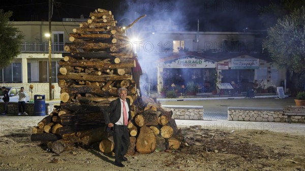 A man in a suit stands at night next to a smoking pile of wood, Mayor of Psinthos, Easter fire Psinthos, Holy Saturday, Easter, Psinthos, Rhodes, Dodecanese, Greek Islands, Greece, Europe