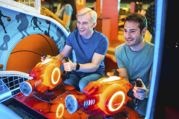 Two young men enjoying a friendly competition on an arcade game machine, illuminated by colorful lights, during a weekend evening at an entertainment venue