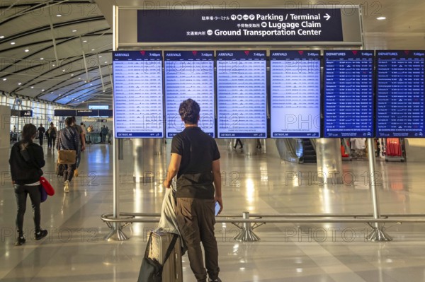 Detroit, Michigan - A traveler looks at the arrivals and departures board at Detroit Metro Airport