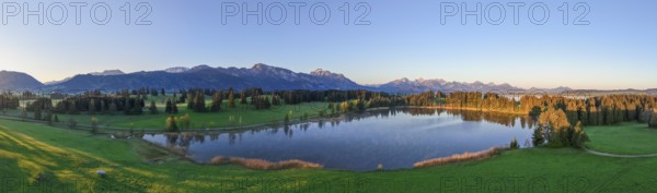 Panoramic view of a lake surrounded by forests and mountains at sunset, Hergratsrieder See, Alps, near Füssen, Ostallgäu, Allgäu, Bavaria, Germany, Europe