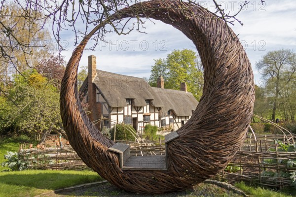 Anne Hathaway's Cottage framed by a round wicker seat, Shottery, Stratford-upon-Avon, Warwickshire, England, United Kingdom, Europe