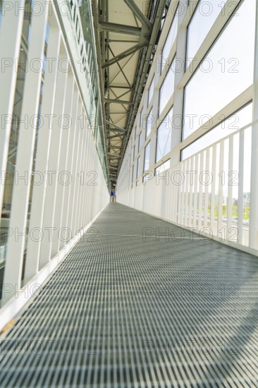 Symmetrical corridor with metal floor and large glass windows, Motorworld Böblingen, Germany, Europe