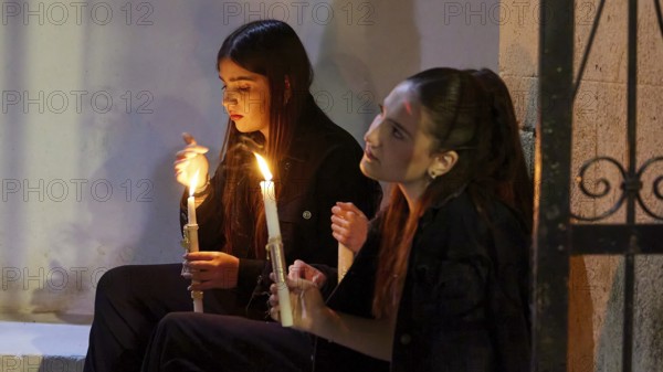 Two girls sit by candlelight, their faces marked by calm and serenity as they quietly contemplate the scene, Holy Light, Easter bonfire Psinthos, Holy Saturday, Easter, Psinthos, Rhodes, Dodecanese, Greek Islands, Greece, Europe