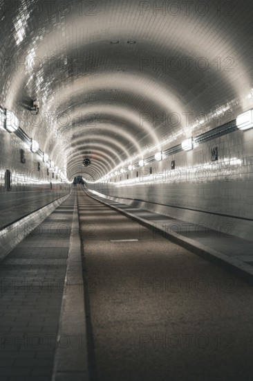 Long, illuminated tiled tunnel with symmetrical curves, old Elbe tunnel, Hamburg, Germany, Europe