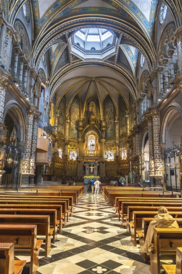 Tourists admiring the interior of santa maria de montserrat basilica, located in the montserrat monastery near barcelona, catalonia, spain