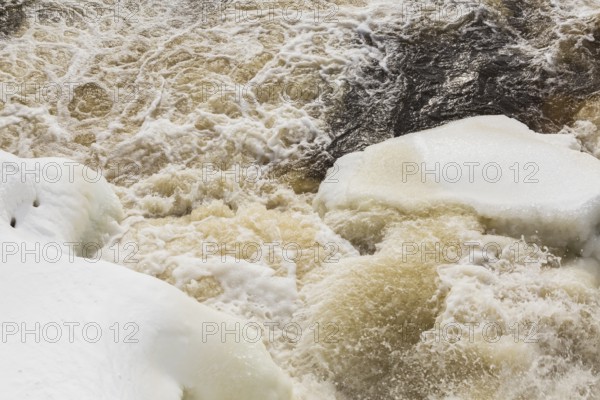 Packed snow with ice and strong water current released through water flow control gates on Mille-Iles river in winter, Old Terrebonne, Lanaudiere, Quebec, Canada, North America