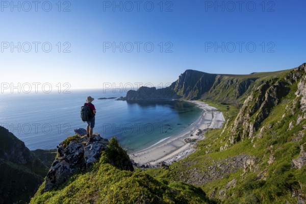 Mountaineer with view of coastal landscape, cliffs with summit Måtind or Måtinden, Høyvika beach and sea, hike to the summit of Måtind, Andøya island, Vesterålen, Nordland, Norway, Europe