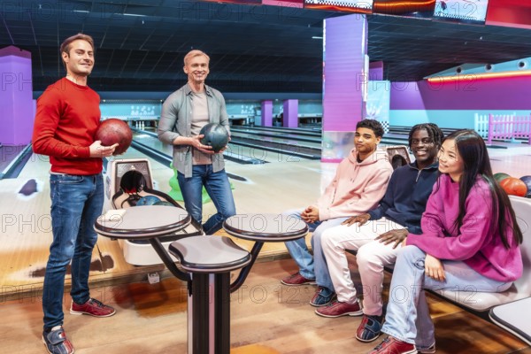 Multi ethnic group of friends enjoying a lively bowling game at the alley, sharing laughter and creating joyful memories together