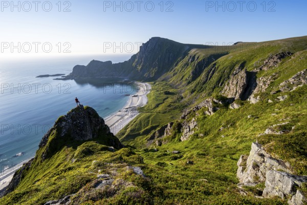 Climber on a rock, view of picturesque coastal landscape, steep coast with peak Måtind or Måtinden, Høyvika beach and sea, hike to the summit of Måtind, Andøya island, Vesterålen, Nordland, Norway, Europe