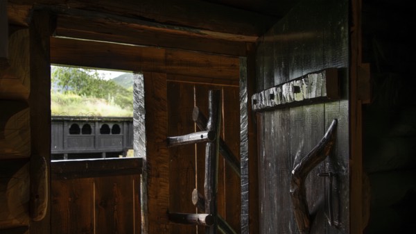 View from a small room in a wooden hut through an open wooden door to a traditional wooden structure outside, backdrop Kristin Lavranstochter film, Jørundgard Middelaldersenter, Olavsweg or Olavsleden, Sel municipality, Gudbrandsdalen, Norway, Europe