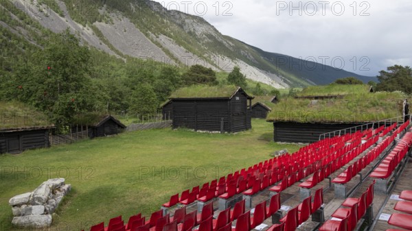 Traditional wooden houses with grass sod roofs, rows of seats with red plastic chairs, ready for an open-air event, backdrop Kristin Lavranstochter film, Jørundgard Middelaldersenter, Olavsweg or Olavsleden, Sel Municipality, Gudbrandsdalen, Norway, Europe