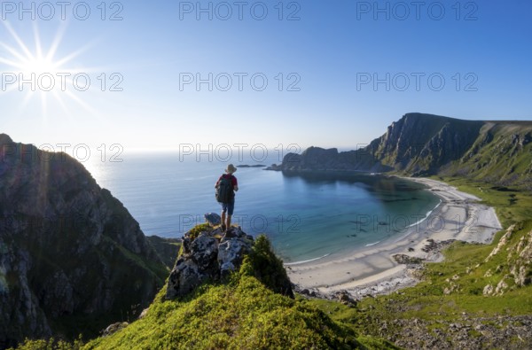 Mountaineer with view of coastal landscape, steep coast with summit Måtind or Måtinden, Høyvika beach and sea, hike to the summit of Måtind, Sun Star, Andøya Island, Vesterålen, Nordland, Norway, Europe