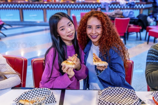 Two young women enjoying pizza slices at a bowling alley restaurant, celebrating friendship and leisure time