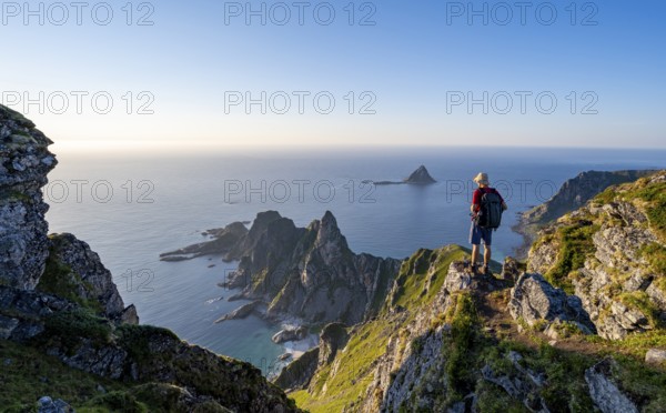 Mountaineer on the summit of Måtind or Måtinden, view of picturesque coastal landscape, rocky coast and sea, Andøya Island, Vesterålen, Nordland, Norway, Europe