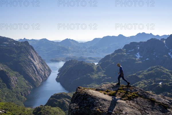 Mountaineer, young man in front of mountain landscape, fjord Trollfjord and mountains, hike to Trollfjord Hytta, at Trollfjord and Raftsund, Lofoten, Nordland, Norway, Europe