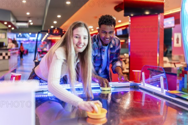 Two young friends enjoying a game of air hockey in a vibrant entertainment center, showcasing youthful energy and leisure activities