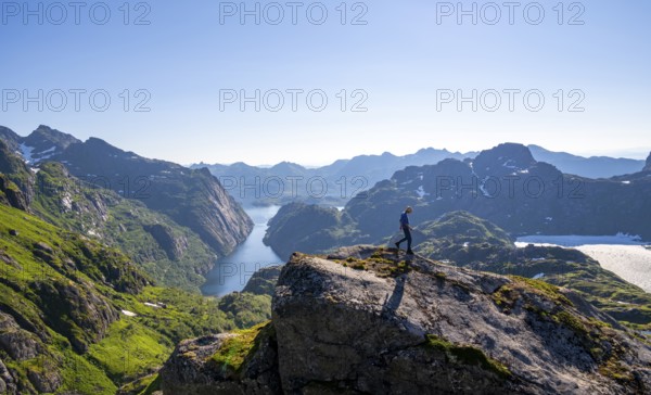 Mountaineer, young man hiking in front of mountain landscape, fjord Trollfjord and mountains, hike to Trollfjord Hytta, at Trollfjord and Raftsund, Lofoten, Nordland, Norway, Europe