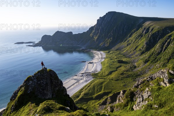 Climber on a rock, view of picturesque coastal landscape, steep coast with peak Måtind or Måtinden, Høyvika beach and sea, hike to the summit of Måtind, Andøya island, Vesterålen, Nordland, Norway, Europe