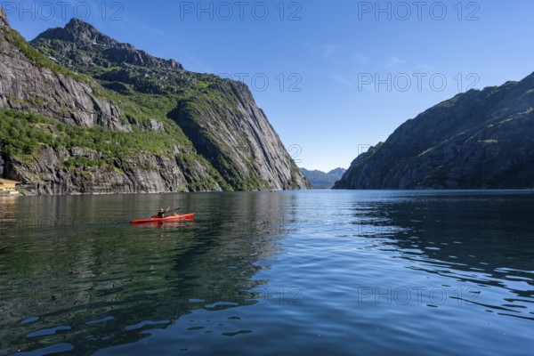 Kayaker with red kayak in the fjord Trollfjord, mountain peaks reflected in the water, fjord landscape and mountains, Lofoten, Nordland, Norway, Europe