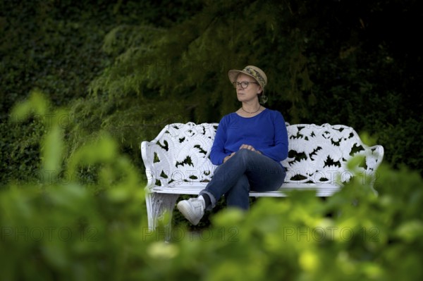 Elderly woman, wearing a sun hat, sitting on a white park bench, pensive, Mainau Island, Constance County, Baden-Württemberg, Germany, Europe