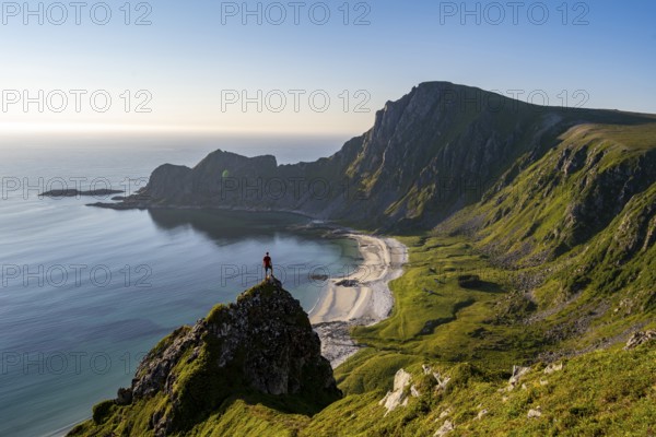 Climber on a rock, view of picturesque coastal landscape, steep coast with peak Måtind or Måtinden, Høyvika beach and sea, hike to the summit of Måtind, Andøya island, Vesterålen, Nordland, Norway, Europe