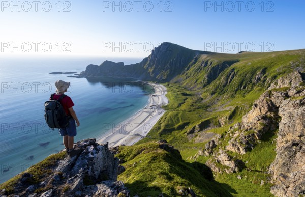 Mountaineer in front of view of coastal landscape, steep coast with summit Måtind or Måtinden, Høyvika beach and sea, hike to the summit of Måtind, Andøya island, Vesterålen, Nordland, Norway, Europe