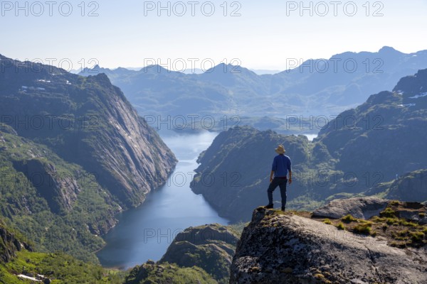 Mountaineer, young man in front of mountain landscape, fjord Trollfjord and mountains, hike to Trollfjord Hytta, at Trollfjord and Raftsund, Lofoten, Nordland, Norway, Europe