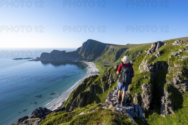 Mountaineer in front of view of coastal landscape, steep coast with summit Måtind or Måtinden, Høyvika beach and sea, hike to the summit of Måtind, Andøya island, Vesterålen, Nordland, Norway, Europe