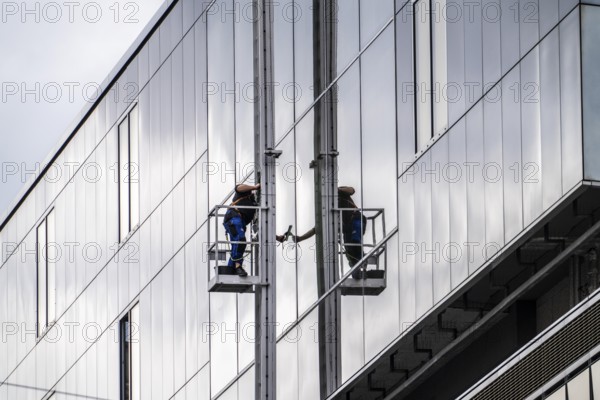 Window cleaner, facade cleaning, window cleaning, on a glass facade in Düsseldorf, ladder cage from the roof