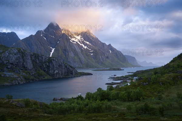 Mountain landscape on the Lofoten Islands. View across the Maervollspollen fjord to mountains in the night sunlight. At night at the time of the midnight sun, clouds and sun. Early summer. Vestvagoya, Lofoten, Norway, Europe