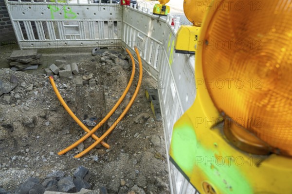 Laying of fibre optic cables, empty conduits are laid under a pavement, in which the actual fibre optic cable is later blown in and connected to the respective house connection or distributor. Essen, North Rhine-Westphalia, Germany, Europe