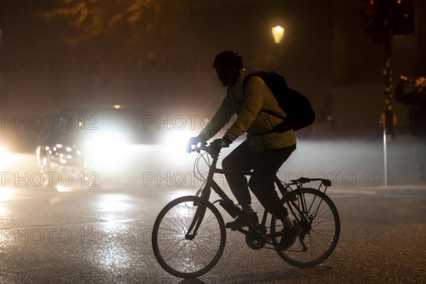 Cyclist, darkness, inner city traffic, fog, autumn, winter, evening traffic, North Rhine-Westphalia, Germany, Europe