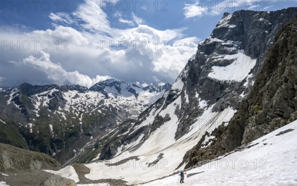 Mountaineer hiking in a snowfield, Nördliche Mörchnerscharte, behind mountain peak Kleiner Mörchner and Greizer Spitze with snow, Berliner Höhenweg, Zillertal Alps, Tyrol, Austria, Europe