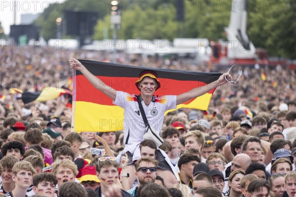 Football fan on shoulders with German flag in the fan zone at the Brandenburg Tor during the quarter-final match between Germany and Spain at the European Football Championship, Berlin, 05/07/2024