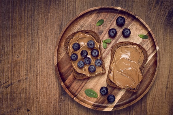 Rye bread with peanut paste and fresh blueberries, top view, no people