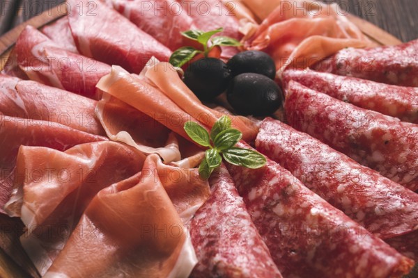 Assortment, sliced meat appetizer, prosciutto, salami and ham, with olives, breakfast, top view, close-up, no people