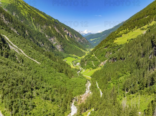 A sunlit valley with green meadows and densely wooded mountains under a clear sky, Stilluptal, Austria, Germany, Europe