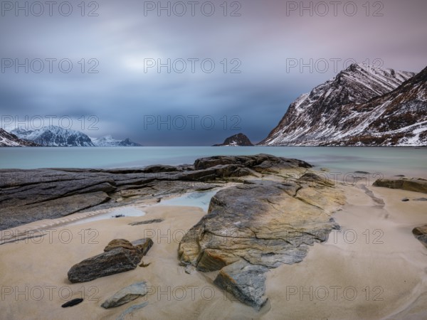 Rocks on Haukland beach, snow-capped mountains in the background, Vestvågøya, Lofoten, Norway, Europe
