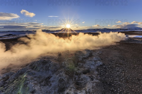 Hot springs and geothermal area in front of mountain landscape in winter, sunbeams, cloudy mood, Hverir, Namafjall, Myvatn, Iceland, Europe