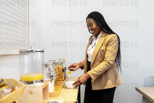 Smiling businesswoman serving breakfast from hotel buffet during business trip, enjoying orange juice and cereals