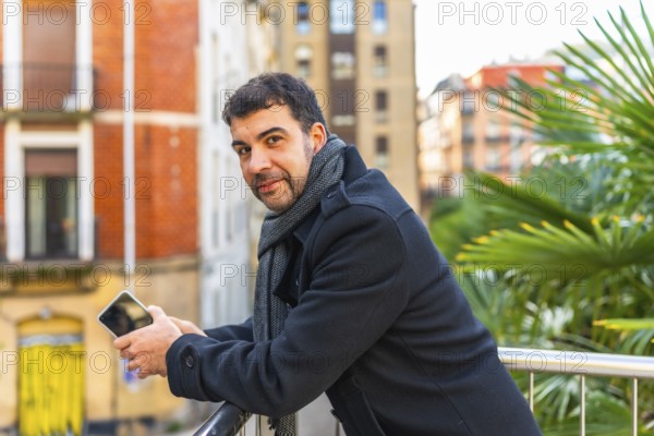 Portrait of a casual businessman smiling at camera leaning on a rail relaxed on a work break in the city